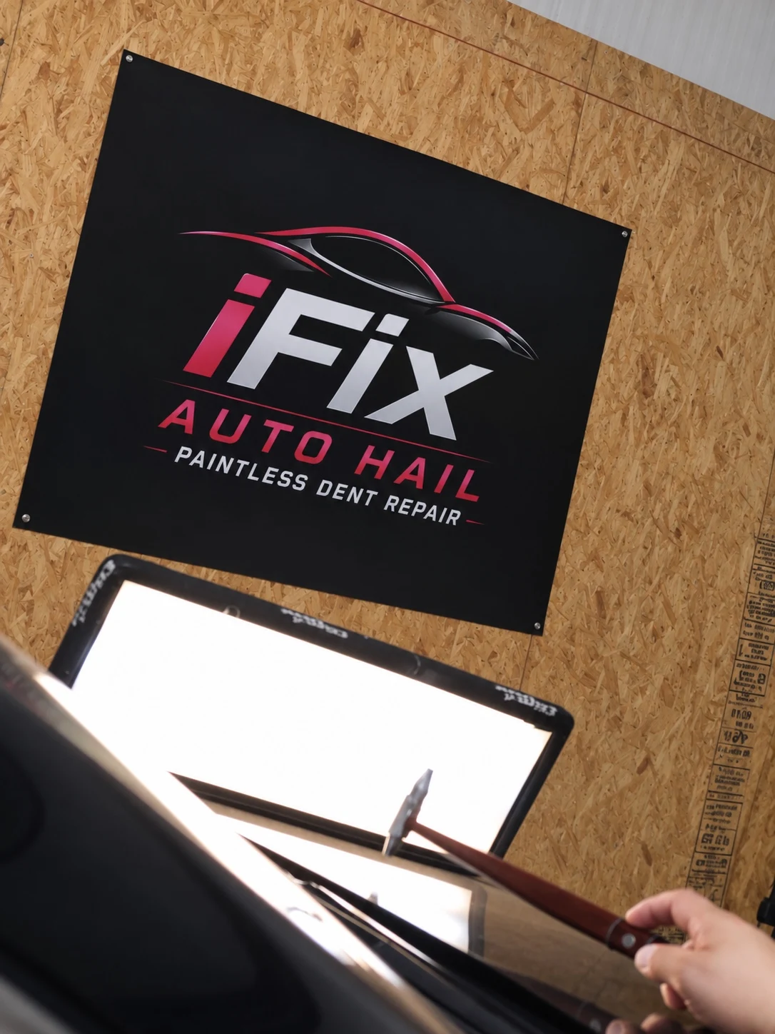 Paintless dent repair work with the iFix Auto Hail logo in the background